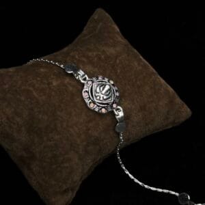 Antique Silver Floral Om Rakhi with Sparkling Pink Accents